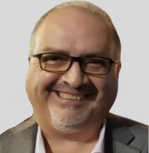Man with glasses and a goatee smiling in a suit